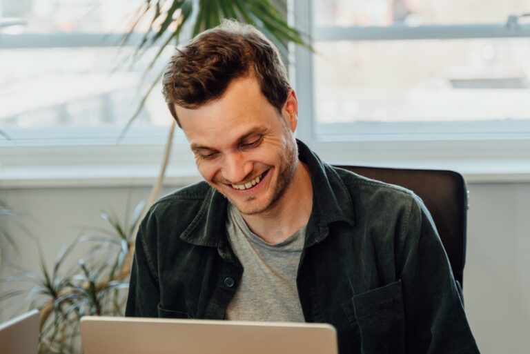 Dave in a green cord shirt smiling at laptop
