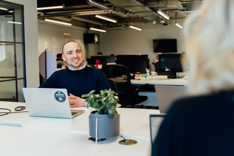 James smiling at desk with work laptop