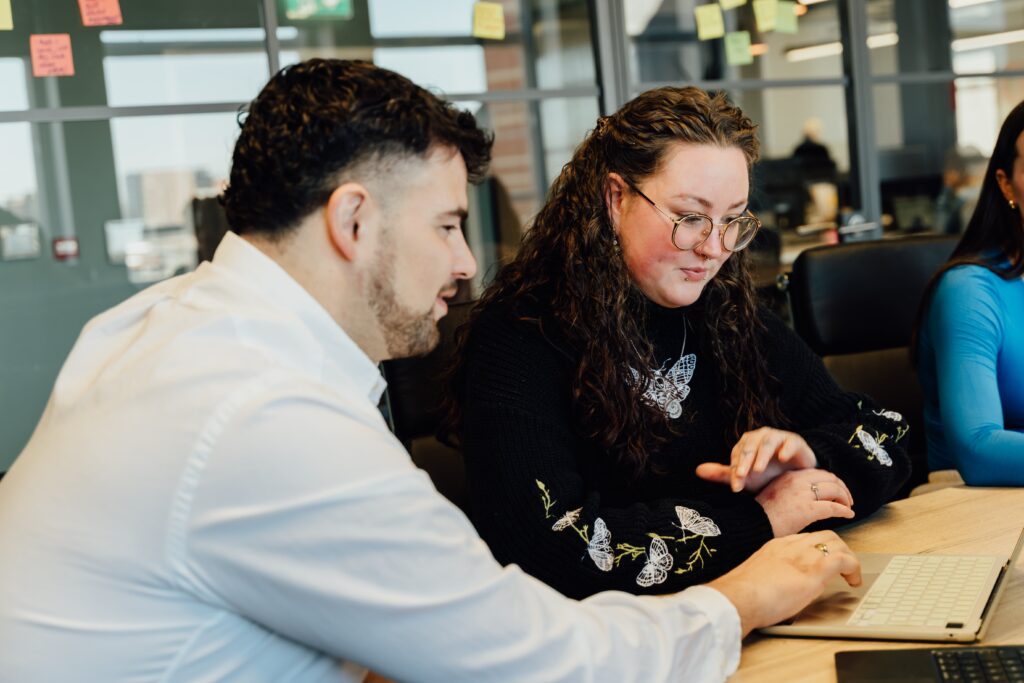 Will and Poppy working together at a desk on their latops
