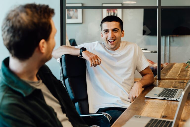 Youssef in a white shirt angled at colleague smiling
